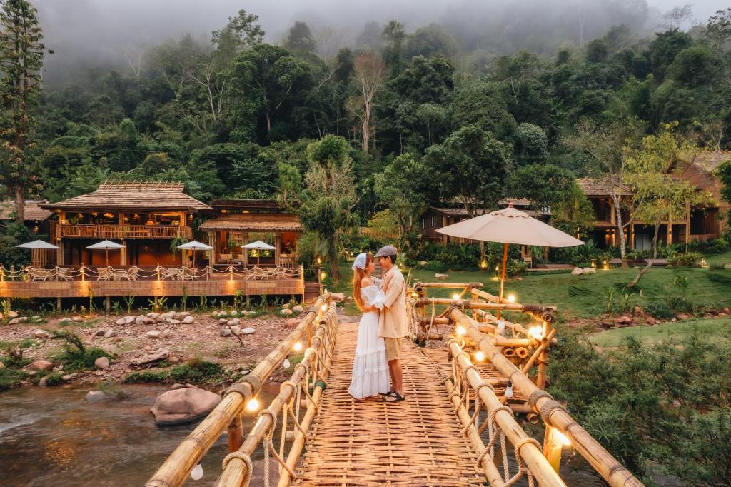 a bride and groom standing on a bridge at อุ่นไอมาง สะปัน in Ban Huai Ti