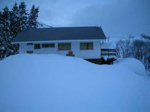 una casa blanca con nieve en el suelo en STI SKI LODGE en Seki