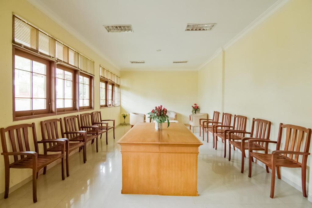 une chambre avec des chaises et une table avec un vase de fleurs dans l'établissement SUPER OYO 3335 Wisma Langen Werdhasih, à Semarang