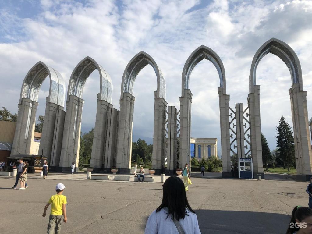 un grupo de personas caminando frente a un edificio con arcos en Auezov Apartment en Almaty