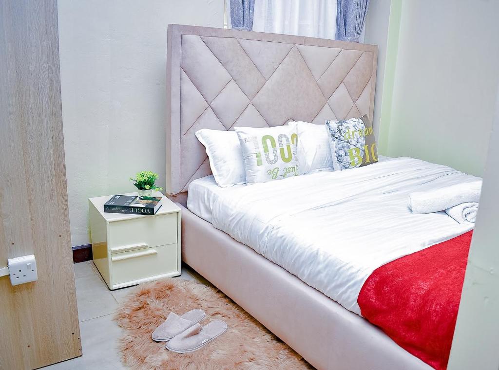 1 dormitorio con cama blanca y cabecero rosa en Belaire BnB Syokimau, en Nairobi