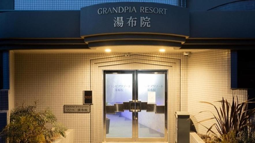 Resort Yufuin - Grandpia Resort Yufuin في يوفو: باب امام مبنى عليه لافته
