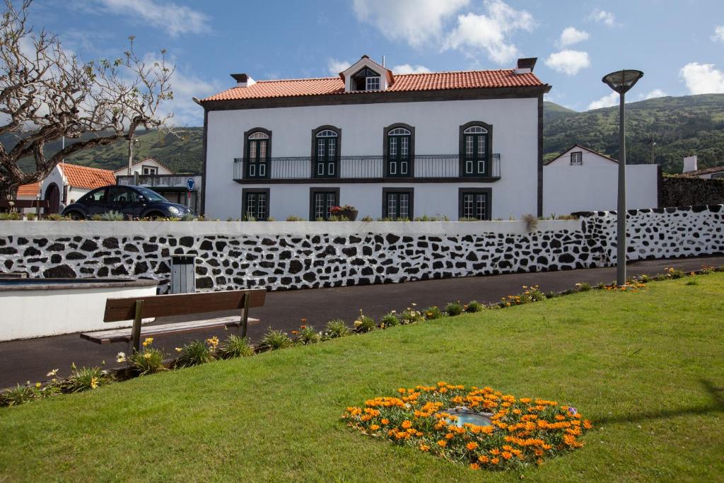 a white building with a fence and a bench and flowers at Pico da Saudade in Prainha de Baixo