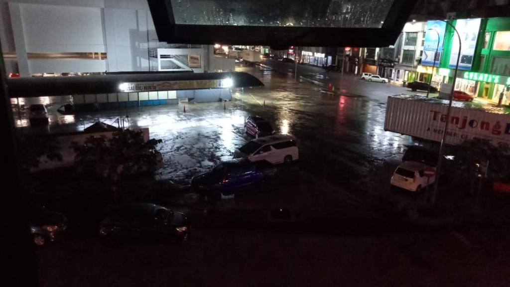 a view of a parking lot with cars in the rain at Dena Moon inn in Kota Bharu