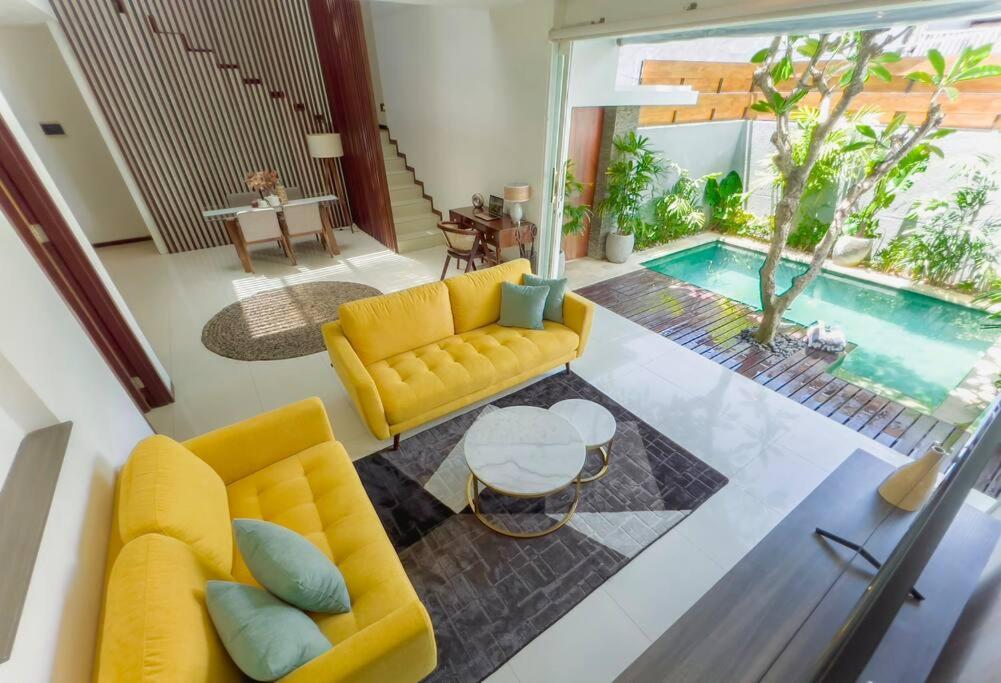 ein Wohnzimmer mit einem gelben Sofa und einem Pool in der Unterkunft The Samya Villa, Berawa Canggu in Denpasar