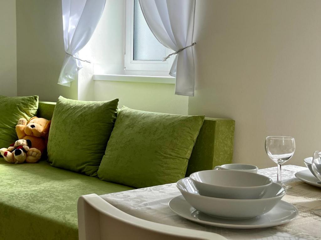 a green couch with a table with a glass of wine at Bezbariérové apartmány se zahrádkou in Chrastava