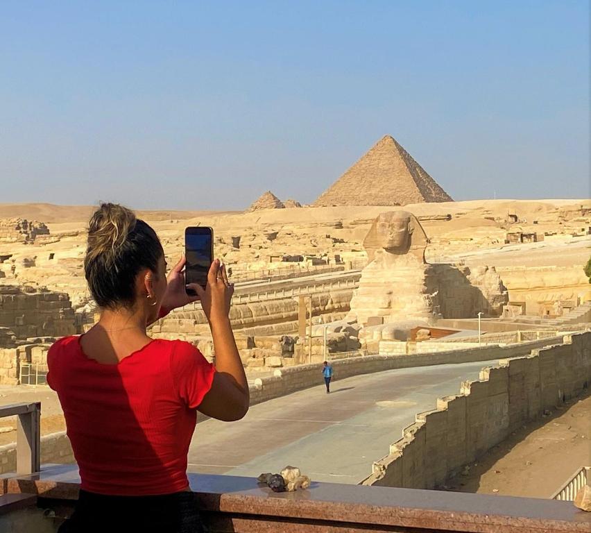 uma mulher a tirar uma foto das pirâmides em Seven Pyramids Inn em Cairo