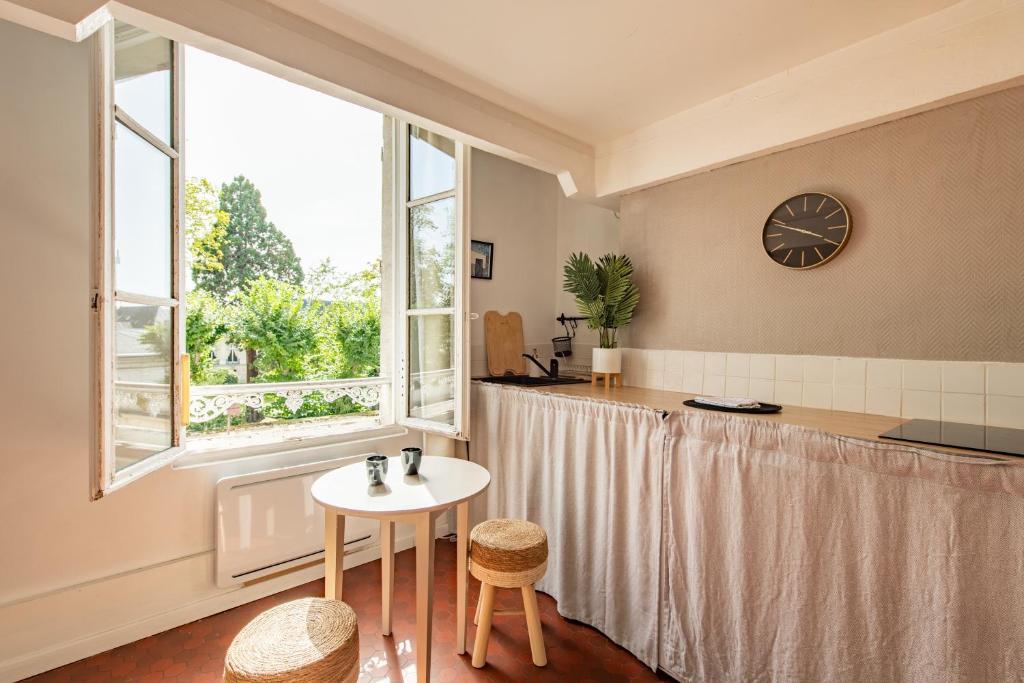 une chambre avec une table et une horloge sur le mur dans l'établissement Charming Apartment in the Heart of Versailles, à Versailles