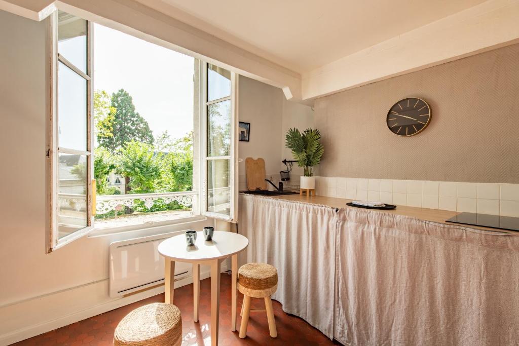 une pièce avec une table et une horloge au mur dans l'établissement Charming Apartment in the Heart of Versailles, à Versailles