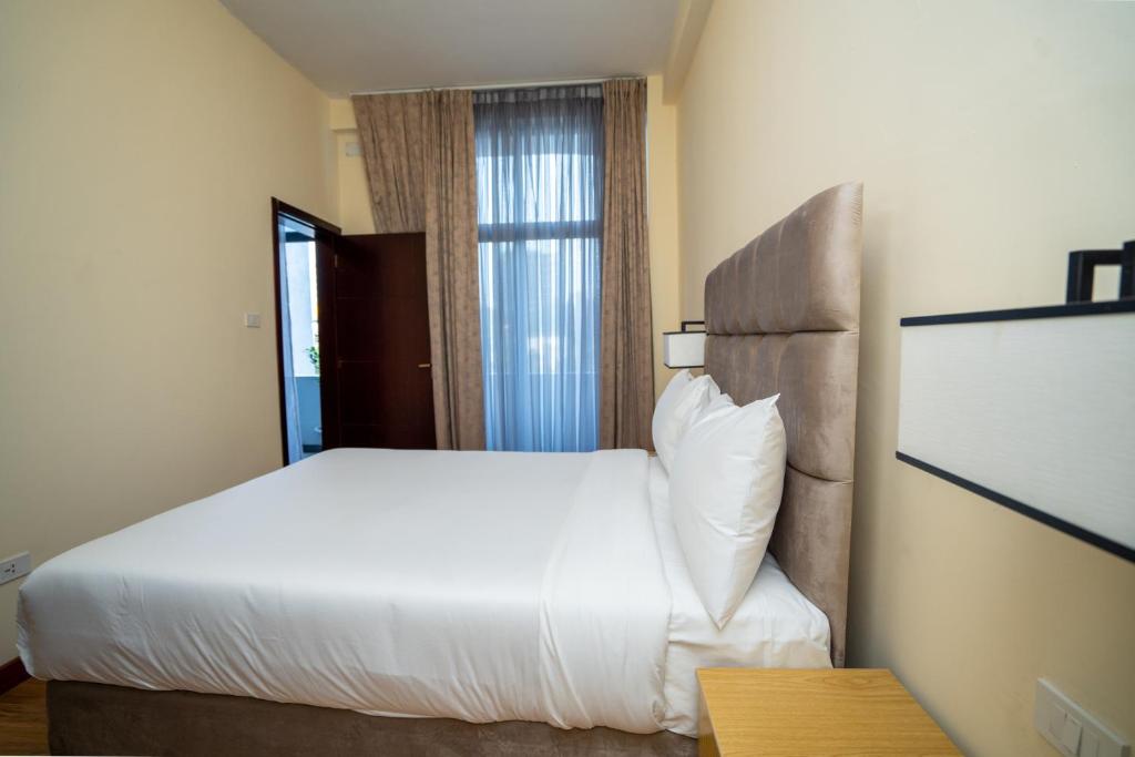 Cette chambre comprend un lit blanc et une fenêtre. dans l'établissement Hagere Apartment Hotel, à Addis-Abeba