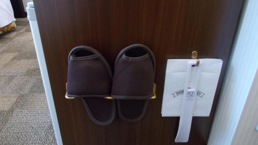 a pair of shoes and a knife on a door at Toyoko Inn Osaka Itami Airport in Toyonaka