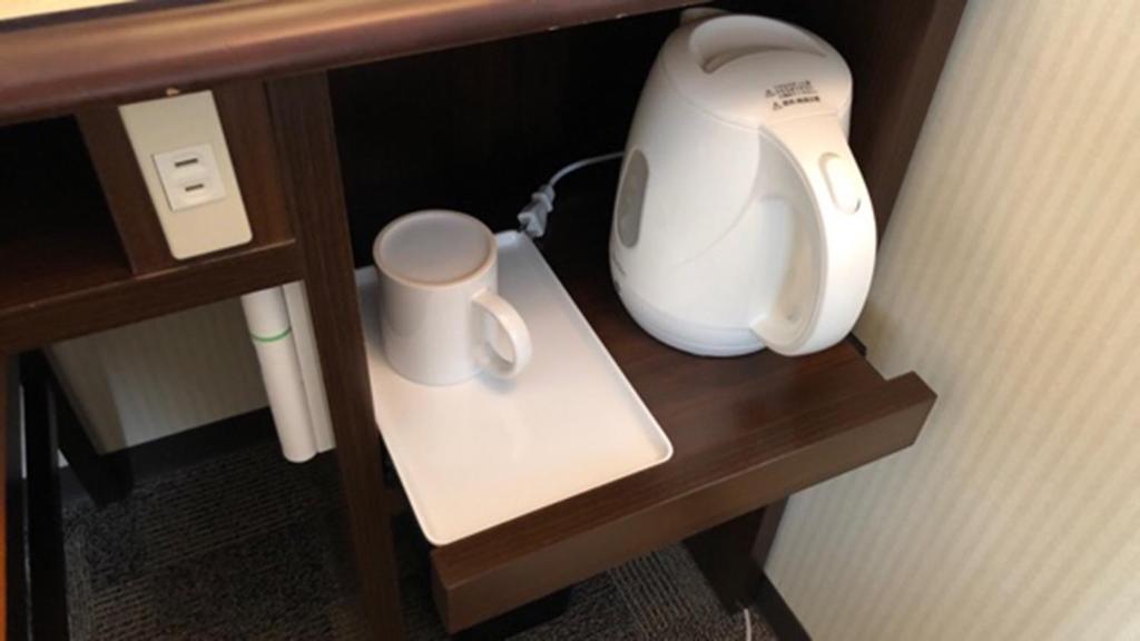 a hair dryer and a cup on a shelf at Toyoko Inn Osaka Itami Airport in Toyonaka
