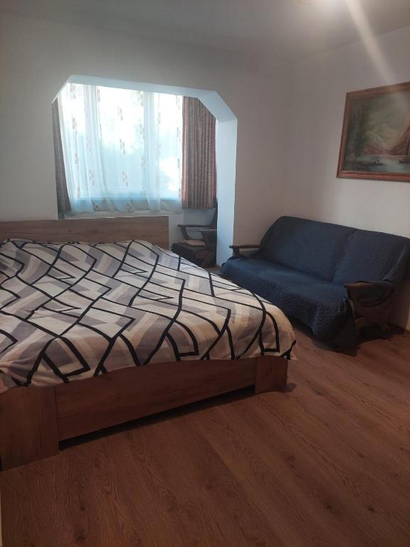 a bedroom with a bed and a blue couch at Apartament Georgian in Băile Tuşnad