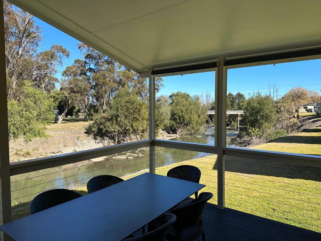 a table and chairs on a screened in porch with a view at Paradise Tourist Park in Tamworth