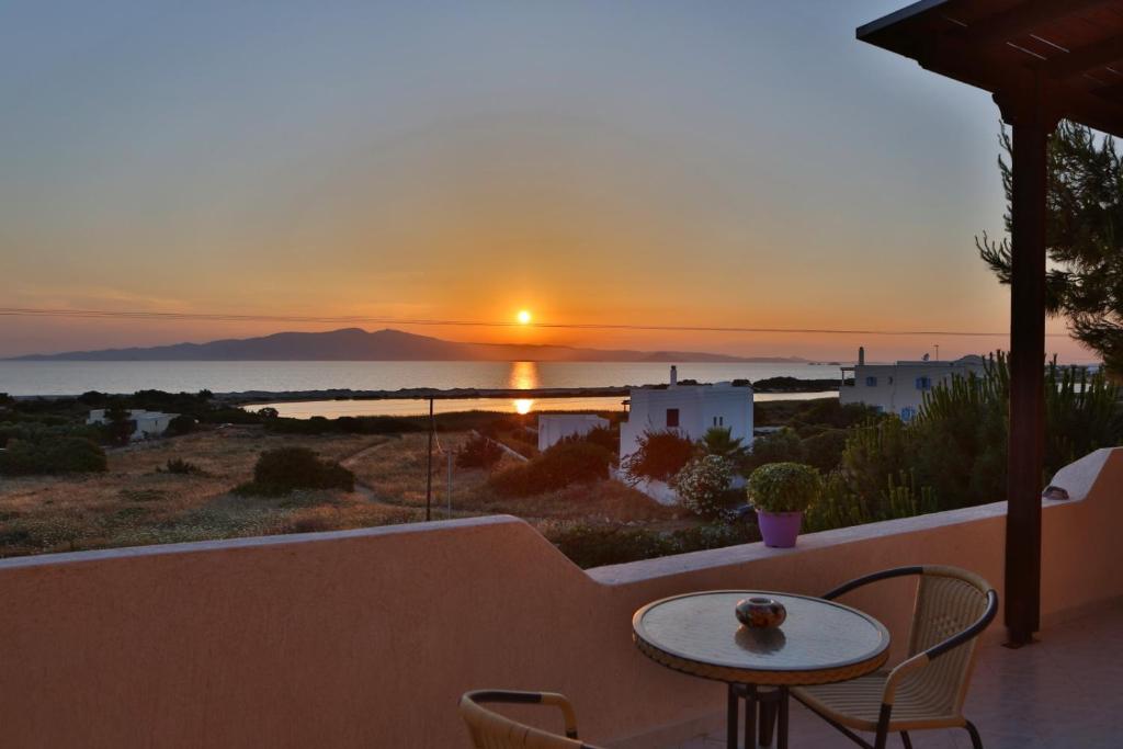 a sunset on a balcony with a table and chairs at Pirgos Naxos in Aliko Beach