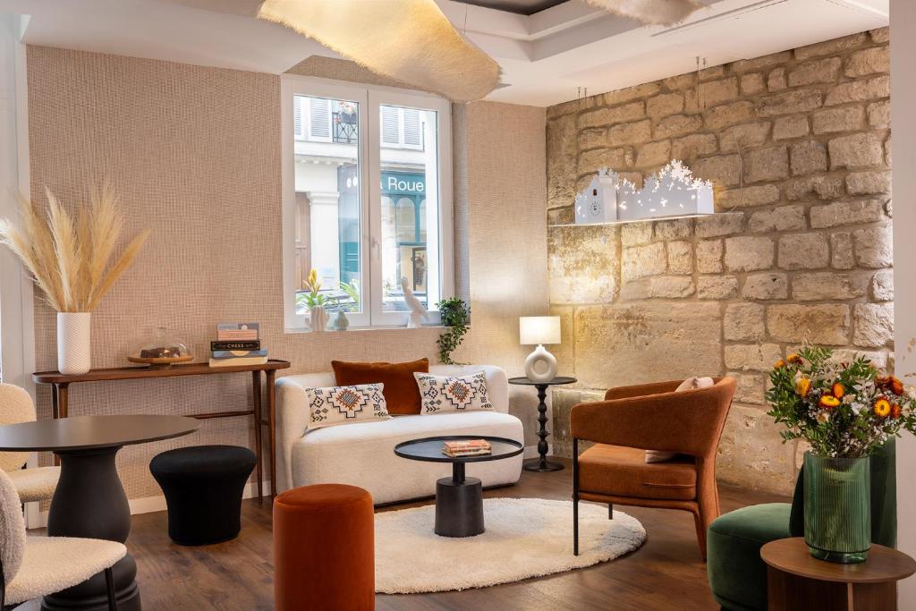 Elle comprend un salon doté d'un mobilier et d'un mur en pierre. dans l'établissement Hotel Chavanel, à Paris