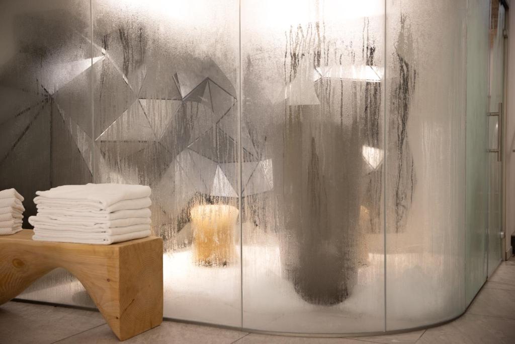a glass shower with a pile of towels on a table at Hôtel Royal in Évian-les-Bains