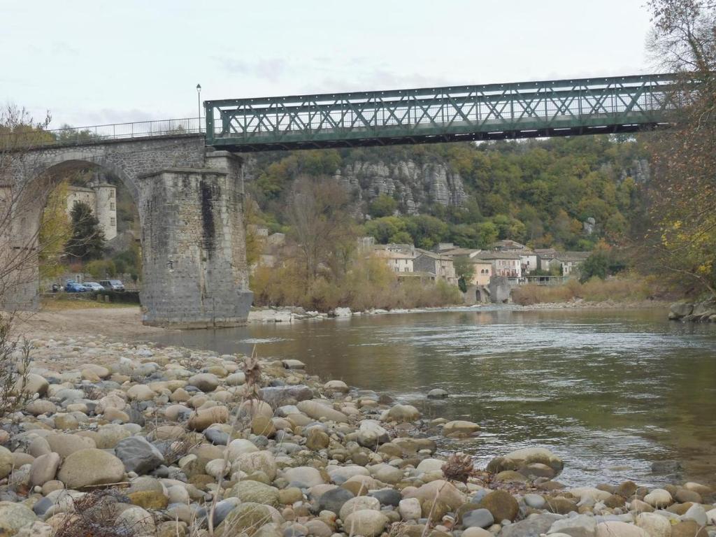 a bridge over a river with rocks and a bridge at Gîte Amour D&#39;ardèche in Saint-Sernin