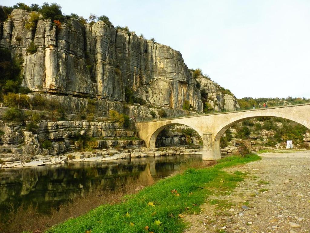 a bridge over a river in front of a mountain at Gîte Amour D&#39;ardèche in Saint-Sernin
