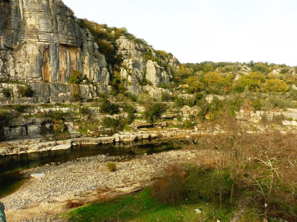 a rock wall next to a body of water at Gîte Amour D&#39;ardèche in Saint-Sernin