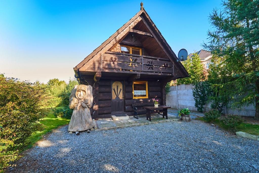 a small log cabin with a statue in front of it at Marel - apartments Domek Kołodziejówka Polanica Zdrój in Polanica-Zdrój