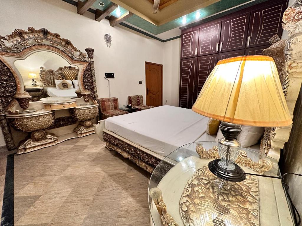 Infinity Hotel في لاهور: غرفة نوم بسرير وطاولة مع مصباح