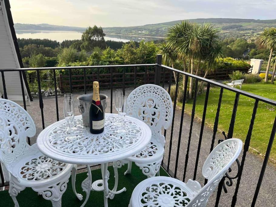 una mesa blanca y sillas con una botella de vino en el balcón en Kylemore Lakeview Retreat en Blessington