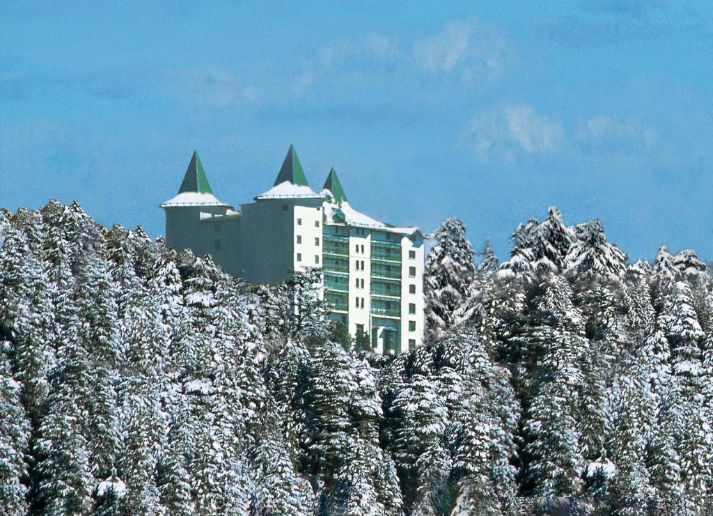 a large building with a mountain range behind it at The Oberoi Cecil in Shimla