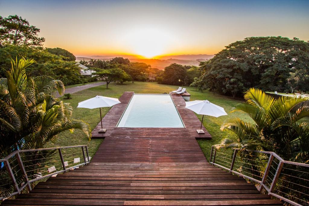 a wooden walkway leading to a pool with umbrellas at Ongoye View Residence - Mtunzini in Mtunzini