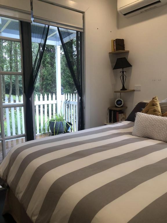 a bedroom with a bed and a large window at Kookaburra Cottage in Bowral