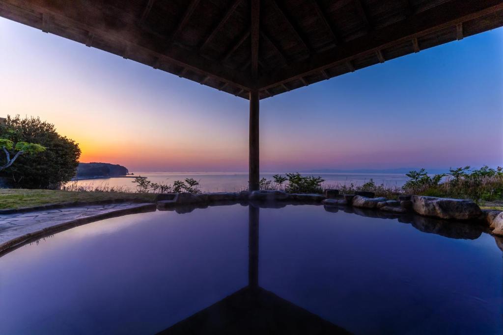 an infinity pool with a sunset in the background at Spa and Resort Hotel Solage Oita Hiji Beppuwan in Beppu