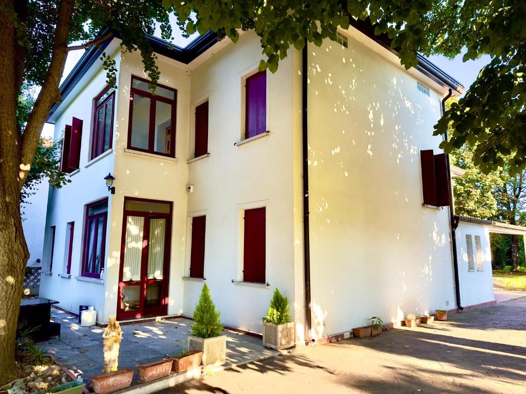 una casa bianca con porte e finestre rosse di ELEGANTE Villa NAKHIL con jacuzzi a Spinea