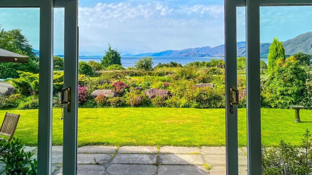 an open door looking out at a garden at Heatherbank Cottage in Onich