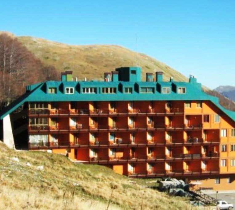 un grand bâtiment au sommet d'une colline dans l'établissement Sguardo nel bosco - Appartamento - Terminillo, à Terminillo