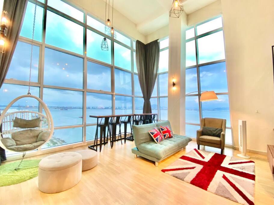 a living room with a large window with a table and chairs at Maritime Suites - Pool Table FULL Seaview 2BR Duplex Suites in Jelutong