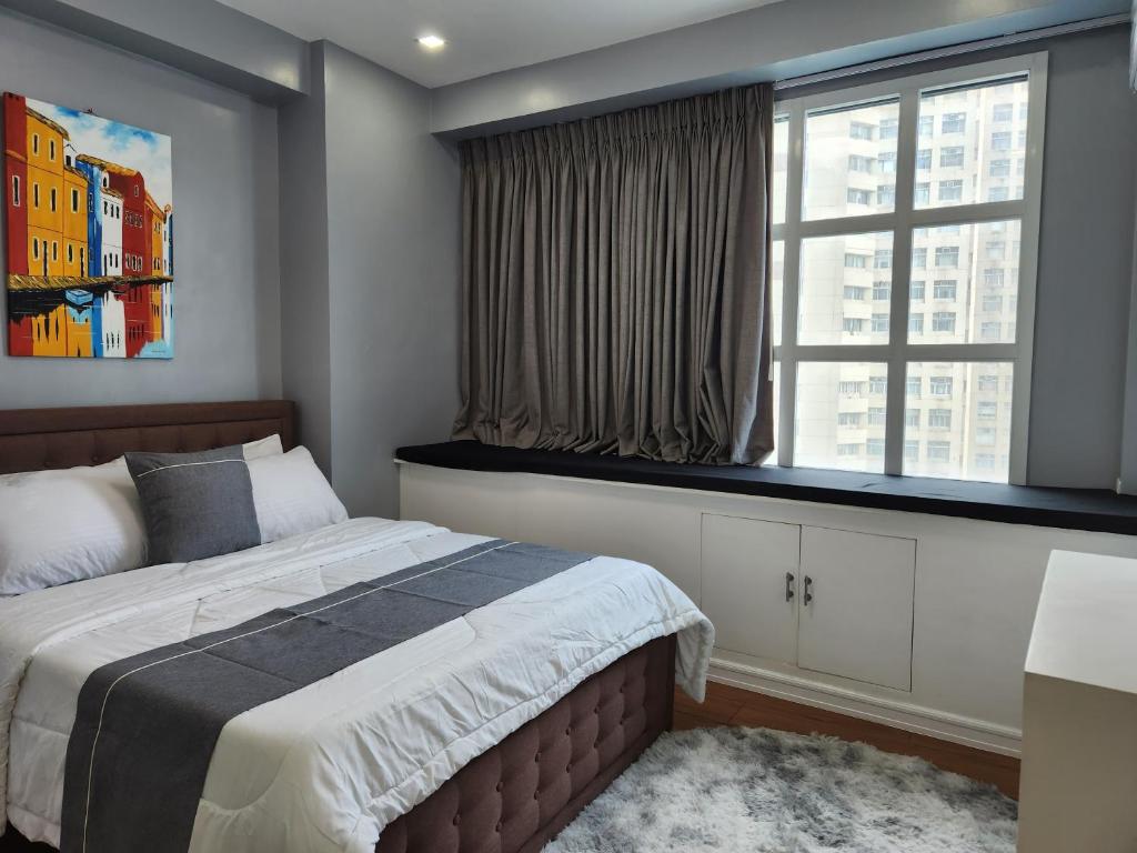 Un dormitorio con una cama grande y una ventana en Cozy and Spacious Condo Unit with Free Netflix en Manila