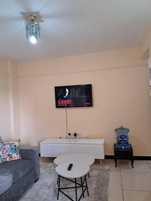 ein Wohnzimmer mit einem Sofa und einem TV an der Wand in der Unterkunft Wenwa Homes South B702037774 (1 bedroom) in Nairobi