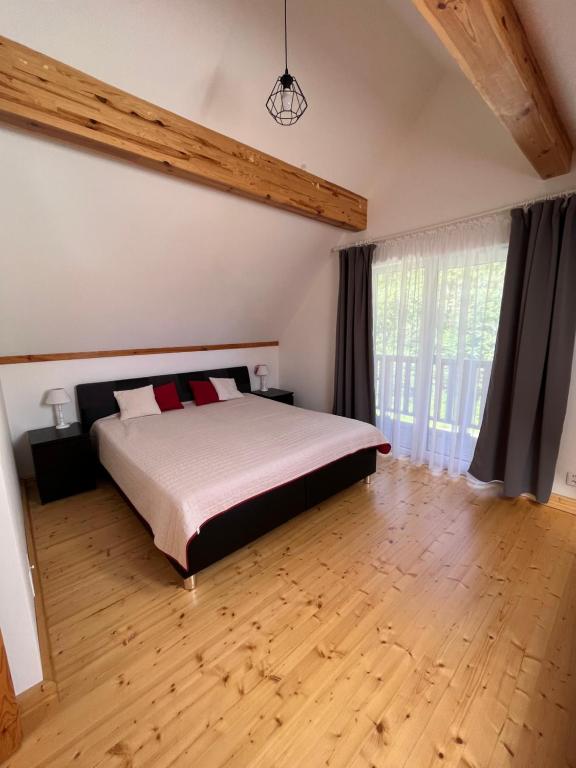 1 dormitorio con 1 cama y suelo de madera en Chata Sára, en Snina