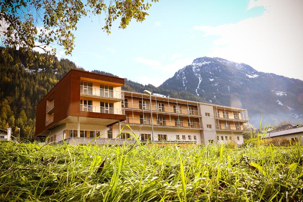 a large building in front of a mountain at Base Aktivhotel Montafon in Sankt Gallenkirch