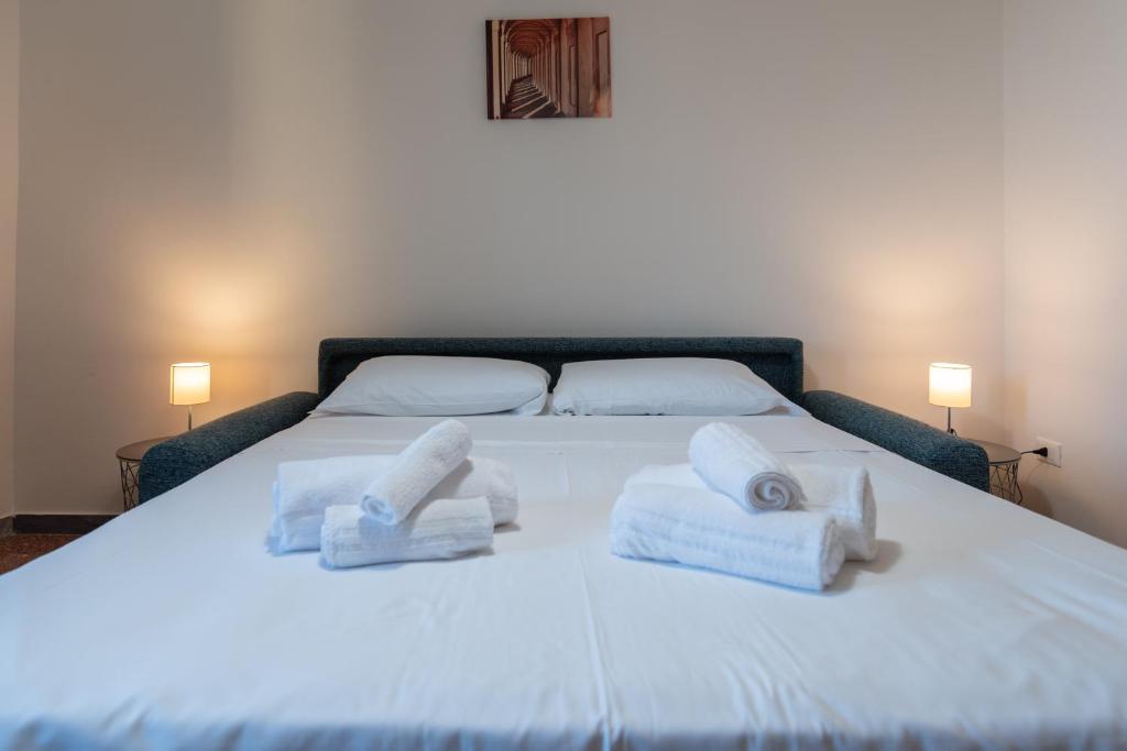 um quarto com uma cama branca e toalhas em Montanari Home zona il S. Orsola em Bolonha