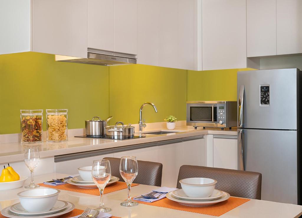 a kitchen with a table with chairs and a refrigerator at Citadines Salcedo Makati in Manila