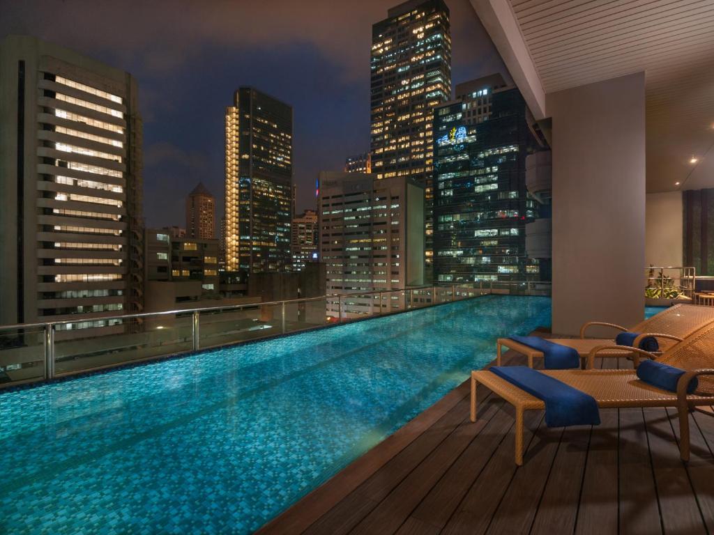a swimming pool on the roof of a building with a city skyline at Citadines Salcedo Makati in Manila