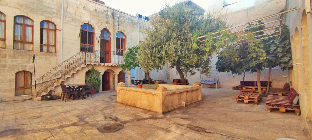 a courtyard with tables and benches and a tree at Taşkıran Boutique Hotel in Urfa