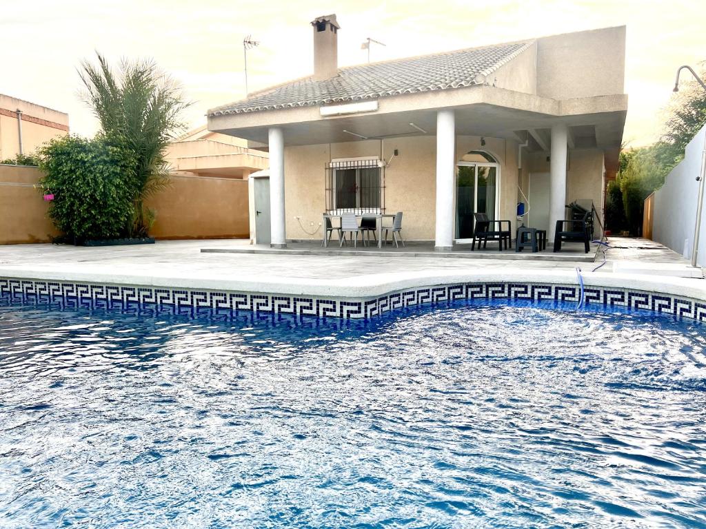 una casa con una piscina de agua frente a ella en CHALET CON PISCINA A 100m DE LA PLAYA LA MANGA, en La Manga del Mar Menor