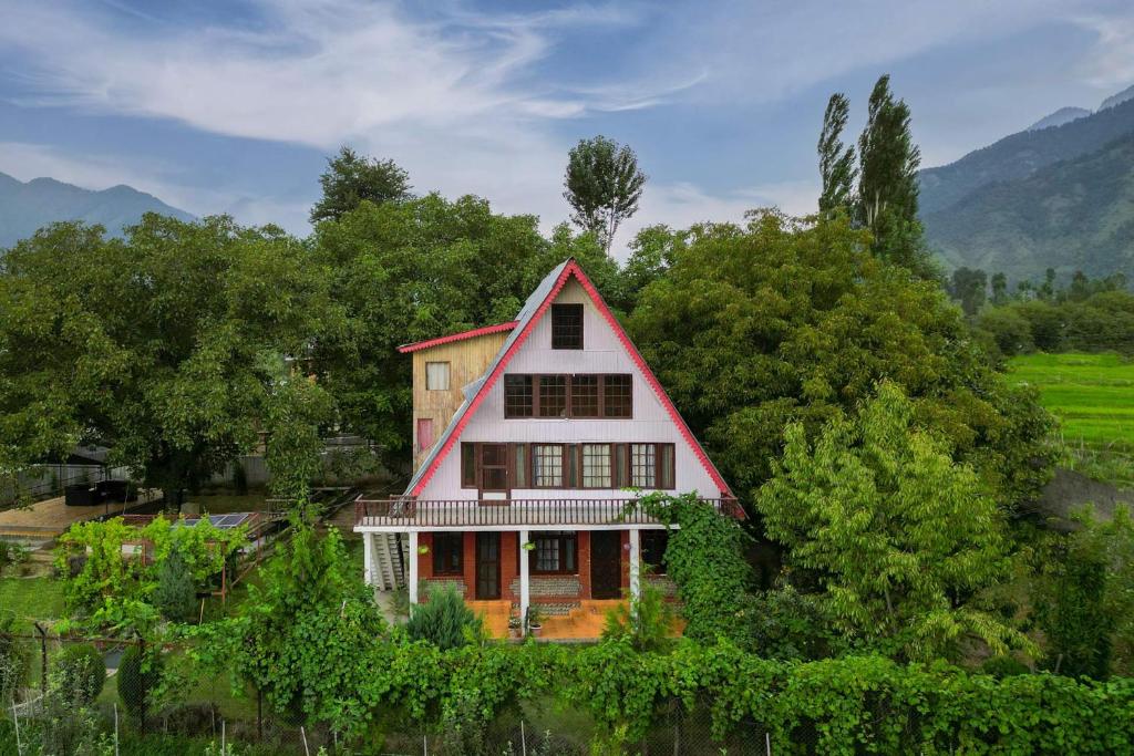 Casa roja y blanca con árboles y montañas en StayVista at Lavender Haze - 3BR Cottage, en Pahalgām