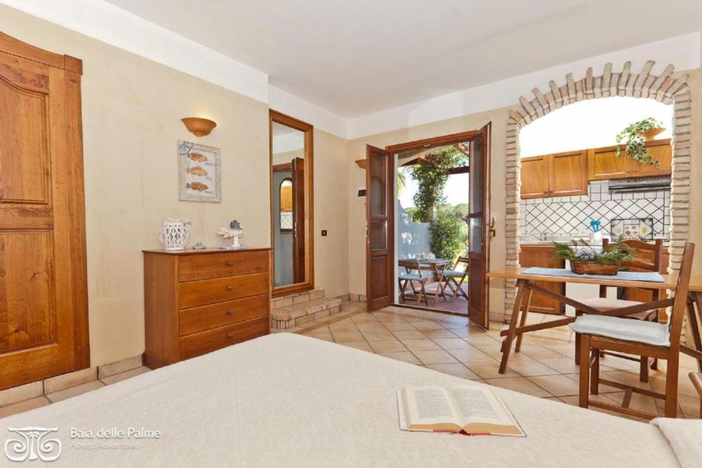 a room with a bed and a table and a kitchen at Residence Baia delle Palme nm1222 in Santa Margherita di Pula