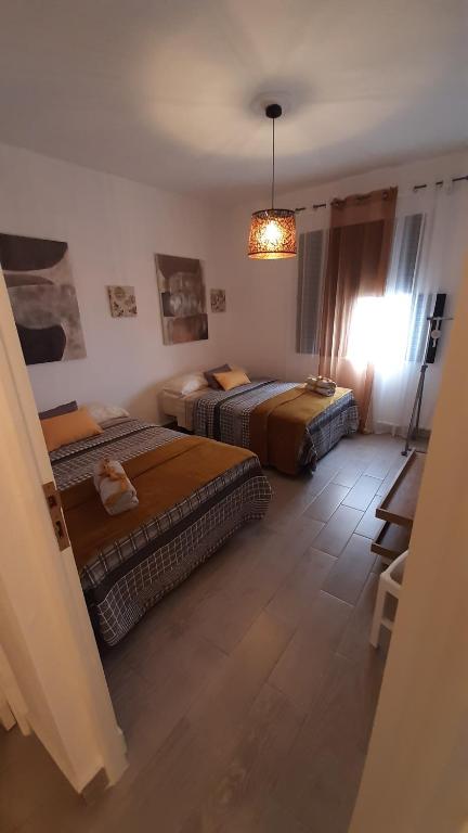 a bedroom with two beds and a chandelier at AbumaHouse in Los Llanos de Aridane