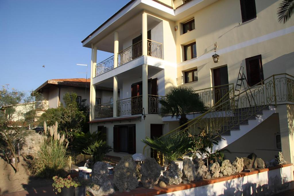 Un grand bâtiment blanc avec des balcons et des escaliers est à votre disposition. dans l'établissement House by the Garden, à Marrùbiu