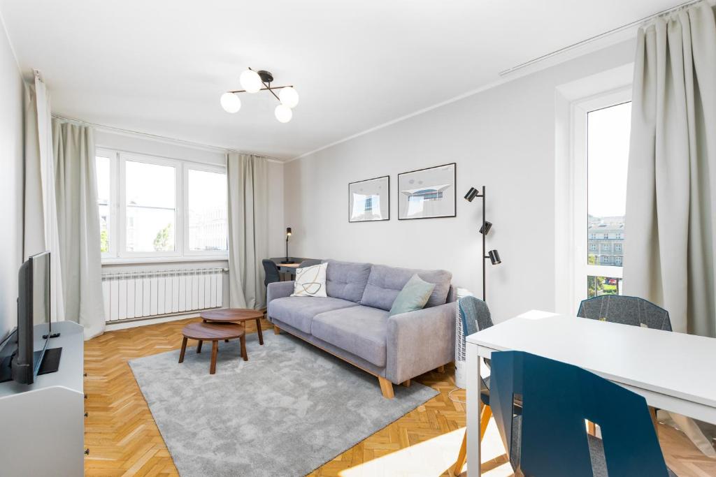 uma sala de estar com um sofá e uma mesa em Pl. Dąbrowskiego 12 by Homeprime em Varsóvia