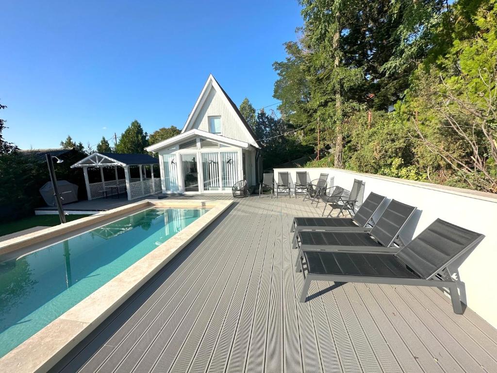 a deck with chairs and a swimming pool next to a house at Tiétek a HÁZ in Mogyoród